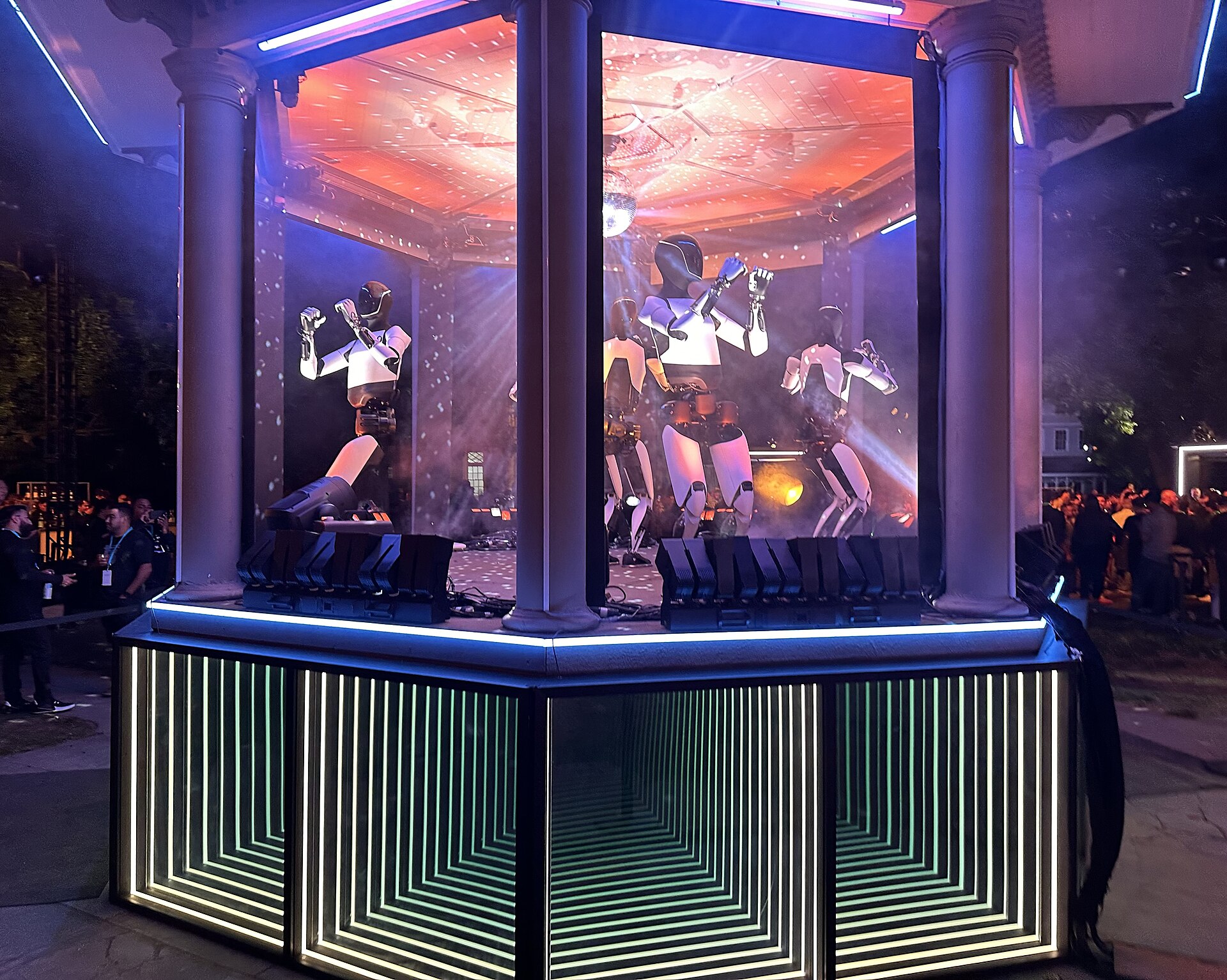 Five Optimus robots dancing on stage